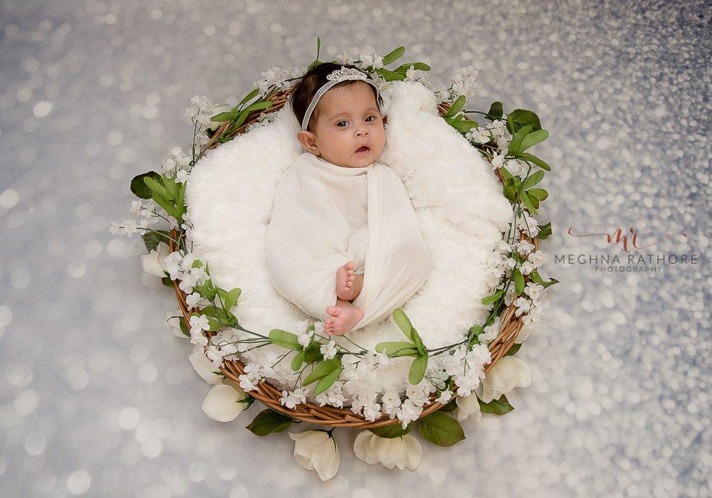 delhi gurgaon photography newborn newborn baby lying in a basket on a white fur with sparkle backdrop meghna rathore photography