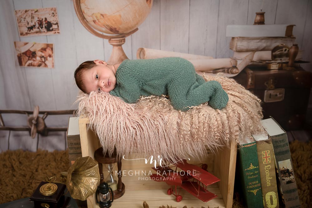 23 days old newborn baby in green colored woolen cloth and around different props at meghna rathore photography at delhi