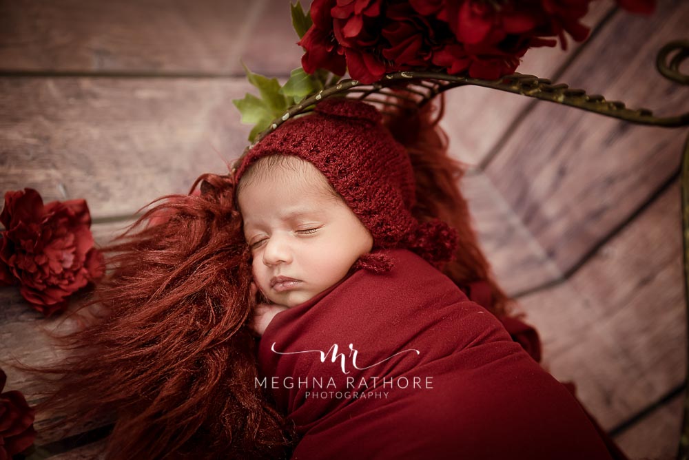 23 days old newborn baby boy with red colored theme and props at meghna rathore photography in delhi