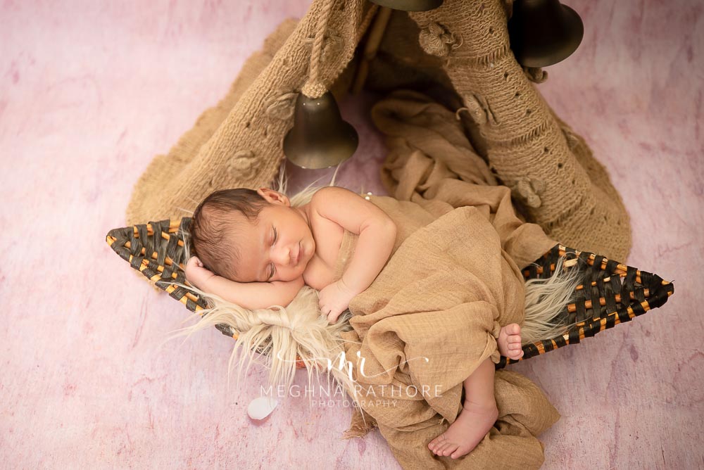 23 days old baby boy in a brown colored props around him at meghna rathore photography in delhi