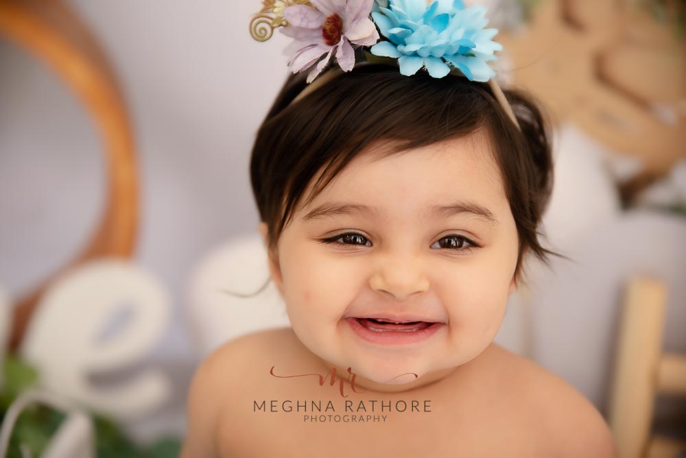 1 year old baby girl close up shot with flower hairband over her head and posing at meghna rathore photography in delhi gurgaon
