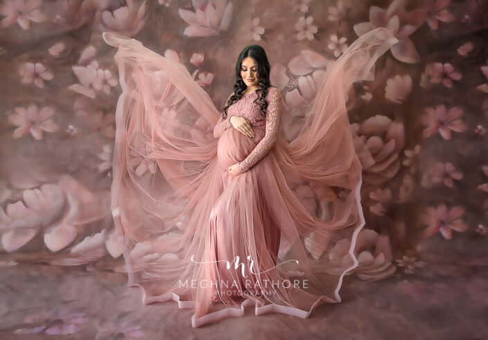 Professional shoot of Mother in peach gown during maternity shoot with floral background in Delhi