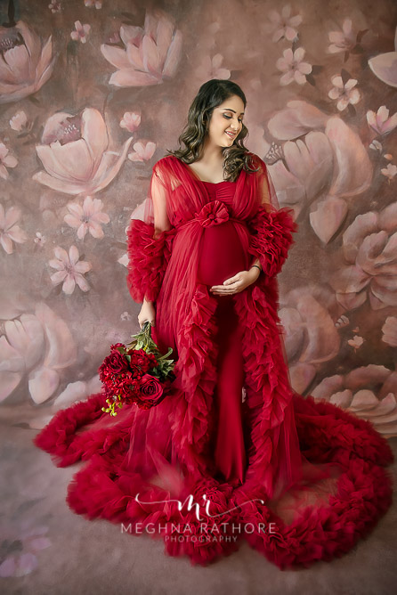 expecting mother red dress holding flowers posing for maternity photo session