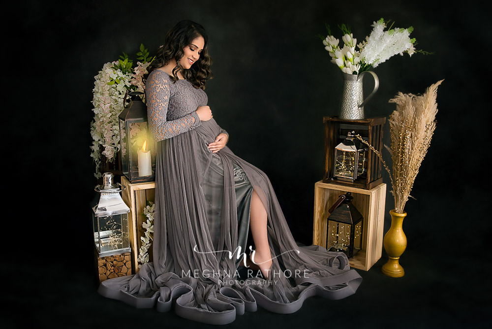 pregnant lady hosing her tummy sitting on a stand with props meghna rathore photography