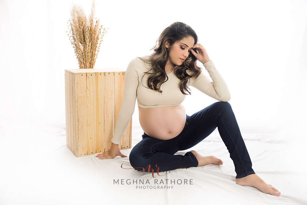wife posing for maternity photo shoot sitting on a floor