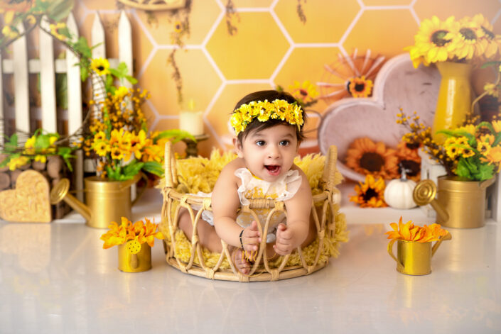 An adorable baby girl nestled in a basket, encircled by bright sunflowers captured by Delhi NCR's best maternal photographer Meghna Rathore.