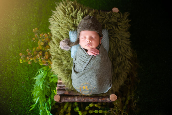 Newborn baby boy peacefully sleeping on a soft green blanket captured by Delhi NCR's best maternal photographer Meghna Rathore.