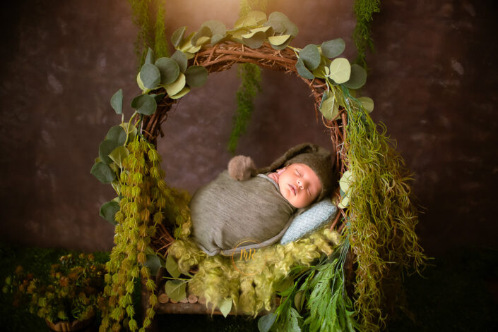 Newborn baby boy napping in a green basket captured by Delhi NCR's best maternal photographer Meghna Rathore.
