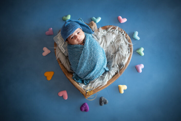 Sweet newborn baby nestled in heart-shaped basket captured by Delhi NCR's best maternal photographer Meghna Rathore.
