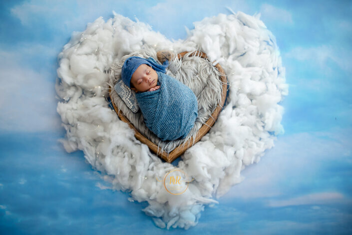A newborn baby peacefully sleeping in a heart-shaped cloud captured by Delhi NCR's best maternal photographer Meghna Rathore.