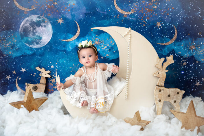 Baby sitting on cloud with moon and stars in the background captured by Delhi NCR's best maternal photographer Meghna Rathore.