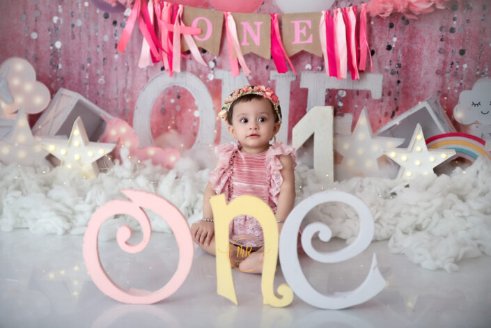 Baby girl sitting in front of a sign that says 'one' captured by Delhi NCR's best maternal photographer Meghna Rathore.