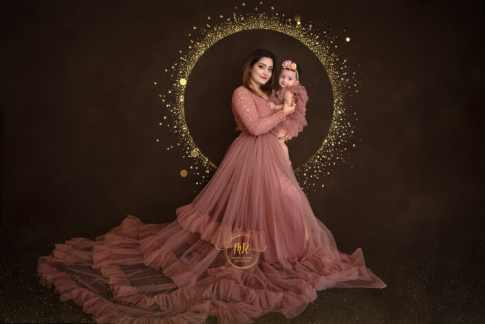 Woman in pink dress holding her baby , smiling warmy captured by Delhi NCR's best maternal photographer Meghna Rathore.