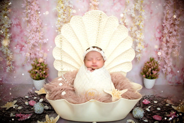 A newborn baby girl peacefully sleeping in a shell captured by Delhi NCR's best maternal photographer Meghna Rathore.