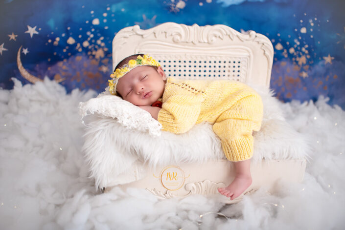 A newborn peacefully sleeping in a feathered white bed captured by Delhi NCR's best maternal photographer Meghna Rathore.