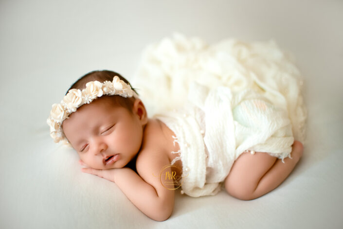 A baby girl in a white costume, looking adorable and colorful captured by Delhi NCR's best maternal photographer Meghna Rathore.