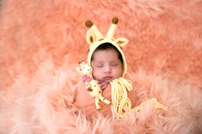 An adorable sleeping baby with a small giraffe toy captured by Delhi NCR's best maternal photographer Meghna Rathore.