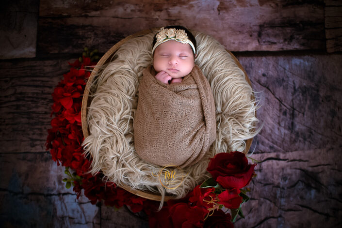 Newborn baby peacefully sleeping in a cozy blanket, surrounded by soft pillows, in a suburban home studio captured by Delhi NCR's best maternal photographer Meghna Rathore.