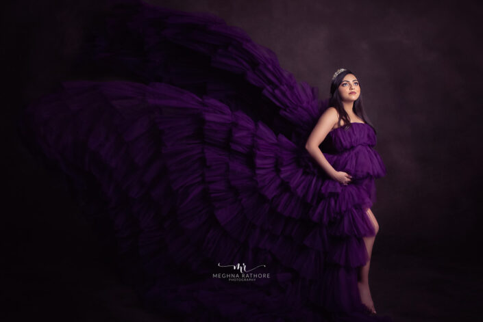 A woman in a purple dress posing with wings captured by Delhi NCR's best maternal photographer Meghna Rathore.