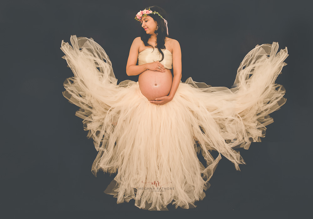 meghna rathore photography maternity photo session mother holding tummy in peach dress with loit of frills