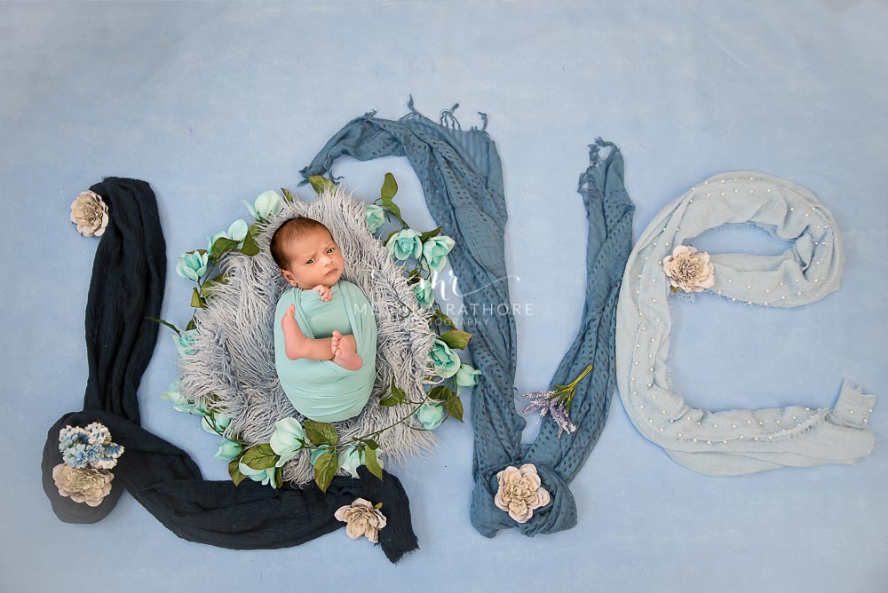 Newborn baby boy posing with the word 'LOVE' written decorated with clothes and posing at meghna rathore photography in delhi