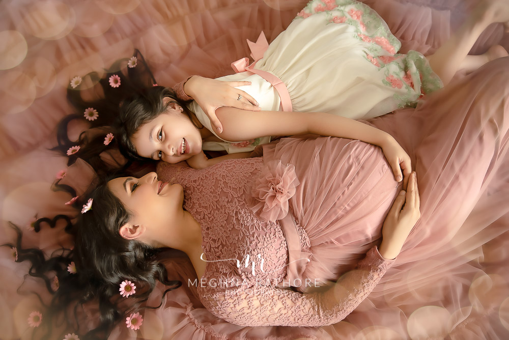 Professional shoot of Mother and daughter in peach gown and white dress during maternity shoot with black background in Delhi
