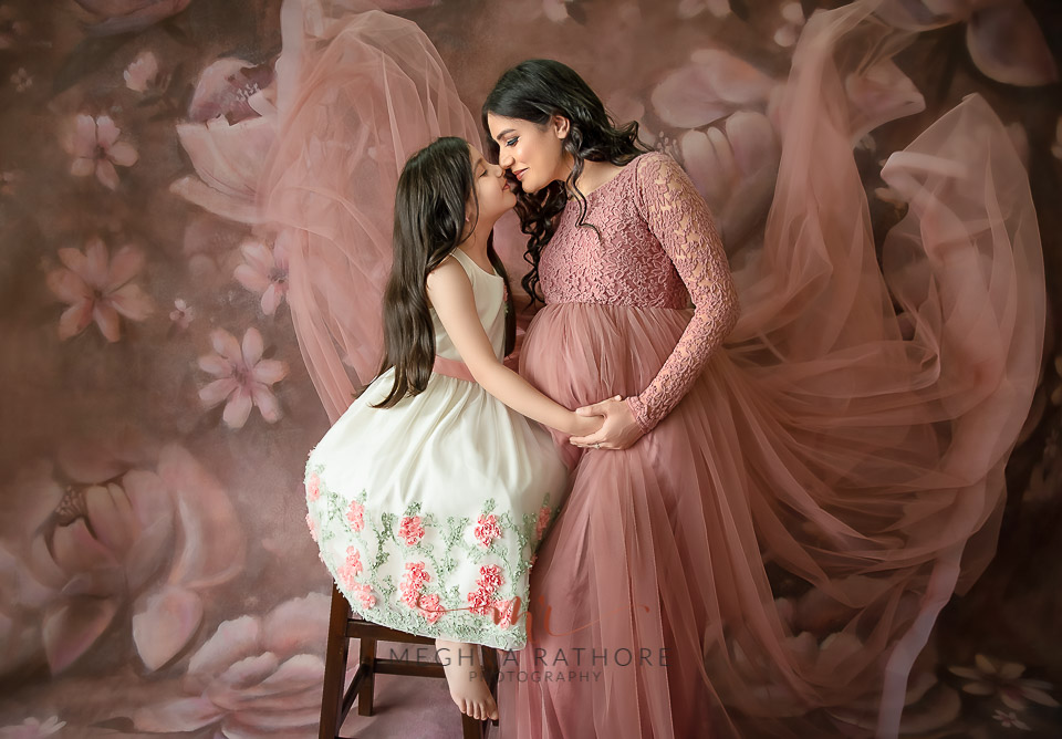Professional shoot of Mother and daughter in peach gown and white dress during maternity shoot with floral background in Delhi