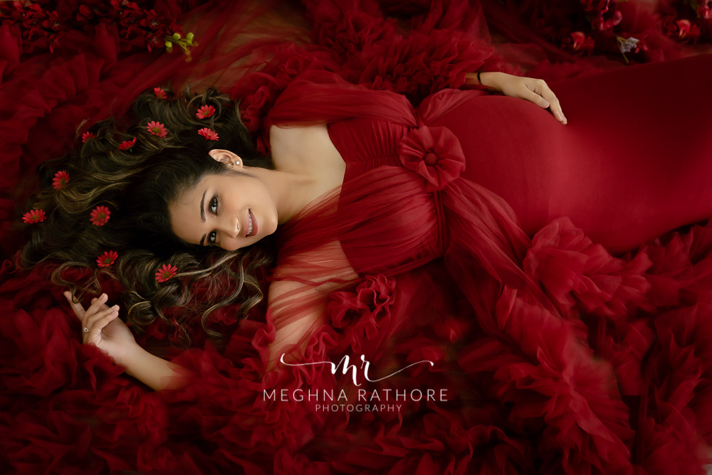 mother lying on a floor wearing red dress with flower decoration