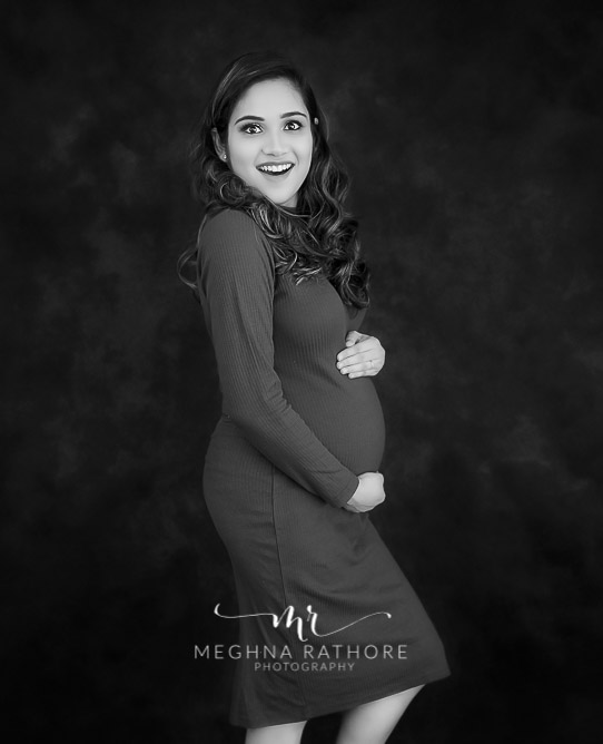 Delhi best maternity photography, mother wearing grey dress with black backdrop
