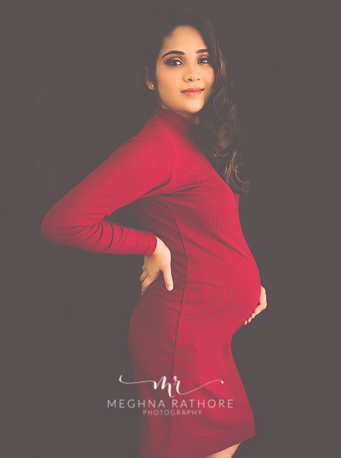 India best maternity photographer in Gurugram photoshoot of woman wearing red dress holding her tummy