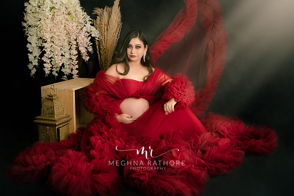 India Best Maternity Photographer in Delhi, Pregnancy Photoshoot Fashion portrait sitting pose in wine red maternity gown