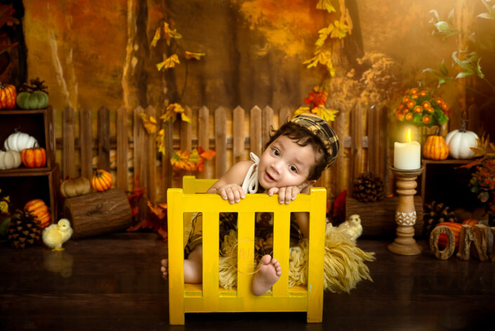 Playing in his fury wooden bed a child in an autumn setting during his pre birthday photoshoot Playing with a pumpkin a child in patterned cloths captured by Meghna Rathore Delhi NCR, Haryana best maternity and child photographer.