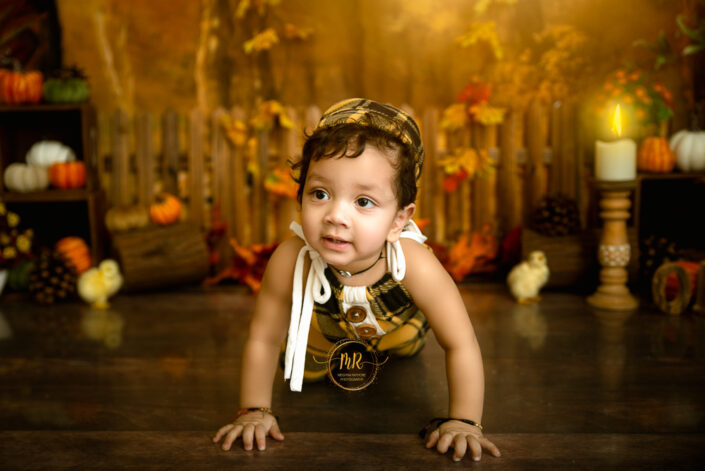 A child wearing a patterned yellow and black cloths walking on his knees during his pre birthday photoshoot captured by Meghna Rathore Delhi NCR, Haryana best maternity and child photographer.