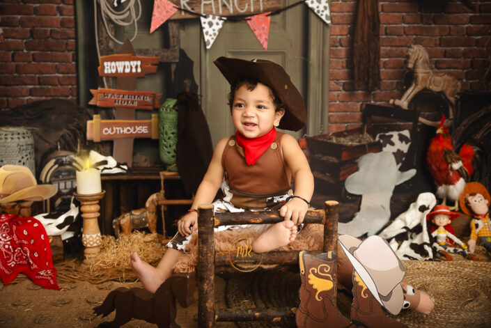 Sitting on his bed and playing with his toy in a ranch like setting a little one year boy during his pre birthday photoshoot captured by Meghna Rathore Delhi NCR, Haryana best maternity and child photographer.