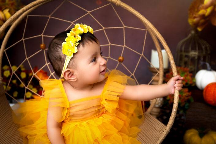 During pre Birthday photoshoot a baby girl giving a side slimily look wearing a floral tiara captured by Meghna Rathore Delhi NCR, Haryana best maternity and child photographer.