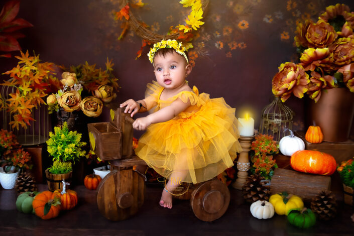 One year baby girl riding a wooden bicycle in an autumn theme captured by Meghna Rathore Delhi NCR, Haryana best maternity and child photographer.