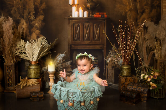 A baby in a decorative setting with candles, dried plants, and vintage furniture, creating a warm, rustic atmosphere captured by Meghna Rathore Delhi NCR, Haryana best maternity and child photographer.