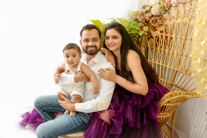 Couple sitting on a big wooden chair with their six month baby boy captured by Meghna Rathore, Delhi NCR's best maternity and child photographer.