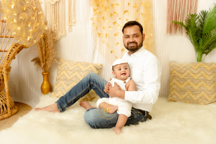 A child and father sitting on a fury carpet and smiling for their photoshoot captured by Meghna Rathore, Delhi NCR's best maternity and child photographer.