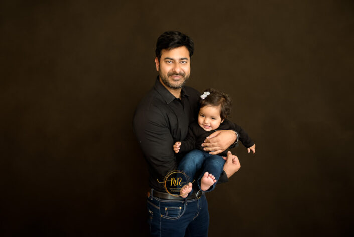 A father holding his baby both in black shirt and jeans captured by Meghna Rathore best maternal and child photographer in Delhi, NCR.