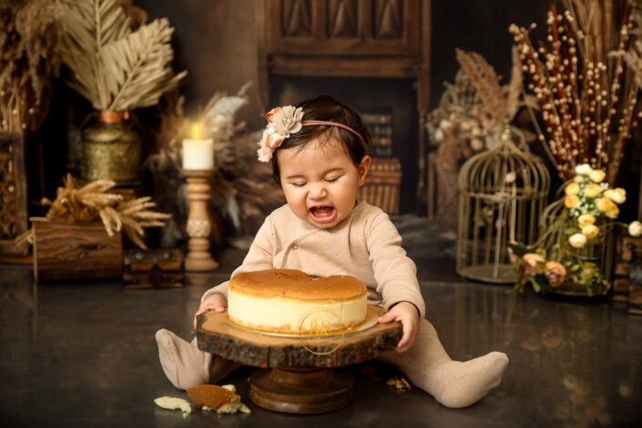 A child with a blurred face indulges in a large cheesecake, surrounded by an elegant, vintage setting adorned with flowers and candles by best kid photographer Meghna Rathore Delhi