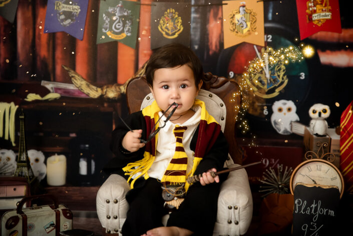 A child in Harry Potter attire sits amidst magical-themed decorations, creating an enchanting atmosphere reminiscent of the beloved book and film series captured by the best maternity and child photographer Meghna Rathore, Delhi NCR, Haryana.