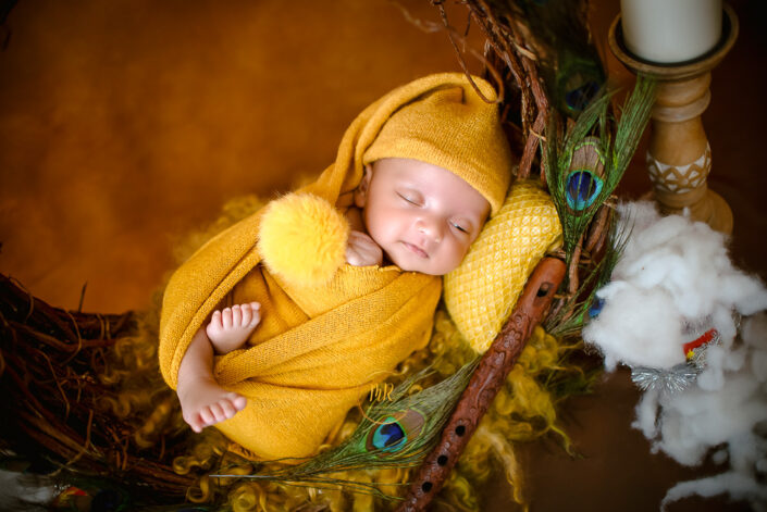 A baby in wrapped in yellow and lying with Krishna flute captured by Meghna Rathore best child and Maternity photographer in Delhi NCR