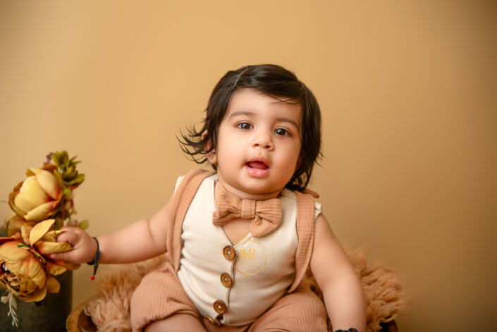 A baby playing with roses wearing a beautiful bow tie during pre Birthday Photoshoot by the best maternity and Pre-Birthday child photographer Meghna Rathore Delhi NCR, Haryana.