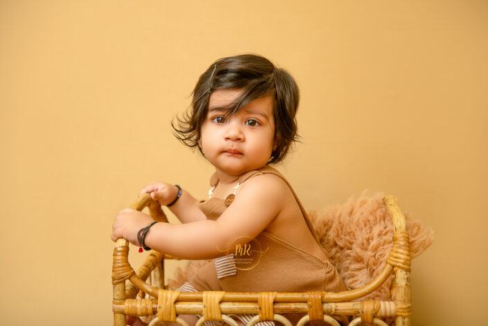 baby photoshoot... 8 months old baby kid sitting in cane bed during photoshoot by meghna delhi best photographer