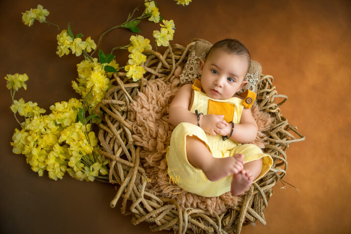 A baby boy in a yellow dress lying on a nest like fury bed captured by Meghna Rathore, Delhi NCR's best maternity and child photographer.