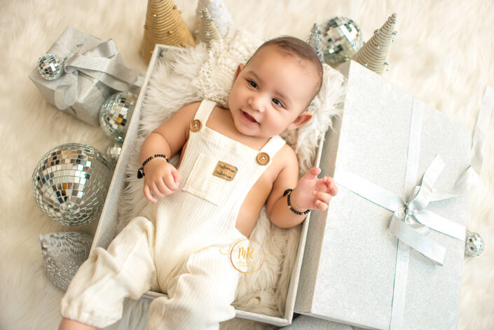 A child in a white dress surrounded by birthday caps and accessories captured by Meghna Rathore, Delhi NCR's best maternity and child photographer.